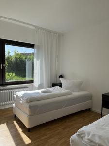 a white bedroom with two beds and a window at Ferienwohnung nähe Montabaur A3 