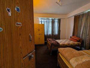 a room with two beds and a door to a bedroom at Mochilero Ostello in Pelling