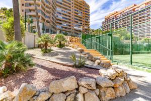 a garden with rocks and trees and buildings at Penthouse sea view, pool, terrace, 2 bedrooms in Cala de Finestrat