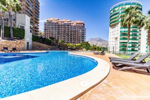 a swimming pool with two chairs and some buildings at Penthouse sea view, pool, terrace, 2 bedrooms in Cala de Finestrat