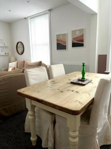a dining room table with white chairs and a couch at The Santiago Suite - sleeps 10 in Southport