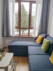 un soggiorno con divano blu e finestra di Studios and Apartments - Semiramida Gardens a Borovets