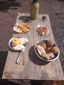 una mesa de picnic de madera con platos de comida. en Cabana juriti en Camaçari
