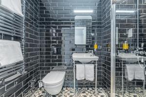 a black tiled bathroom with a toilet and a sink at Hotel Aska in Reykjavík