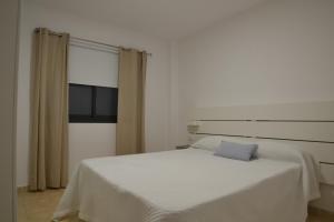 1 dormitorio con cama blanca y almohada azul en LEOAN,sL, en Los Llanos de Aridane