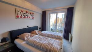 - une chambre avec 2 lits et une fenêtre dans l'établissement Zeedijk Koksijde, à Coxyde