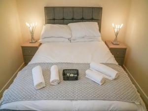 a bed with towels and a clock on it at Pass the Keys Stylish 4 bedroom home in Nottingham