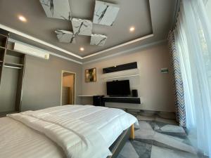 a bedroom with a bed and a flat screen tv at Sutalawadee Resort in Ban Prasat