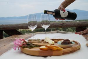 a person pouring wine into two wine glasses at Assos Ada Hotel in Ayvacık