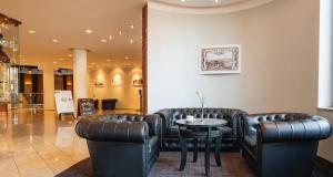 a waiting room with leather furniture and a table at Victor's Residenz-Hotel Frankenthal in Frankenthal