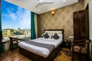 a bedroom with a bed and a large window at Hotel Wisteria Zirakpur - Main Highway Hotel in Zirakpur