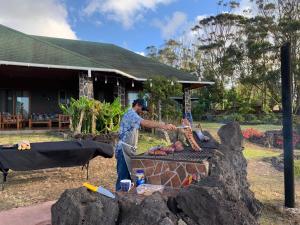 un homme cuisinant des hot-dogs sur un grill dans l'établissement Heva Eco Lodge, à Hanga Roa