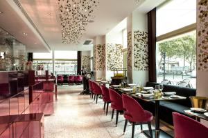 Fauchon l'Hôtel Paris في باريس: مطعم فيه كراسي حمراء وطاولات وبار