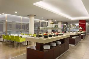 a restaurant with tables and yellow chairs and plates at Ramada Plaza by Wyndham Bucharest Convention Center in Bucharest