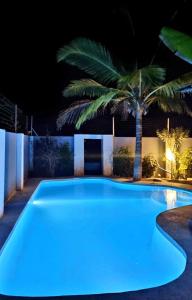 a swimming pool lit up at night with a palm tree at Villa Kikadini in Jambiani
