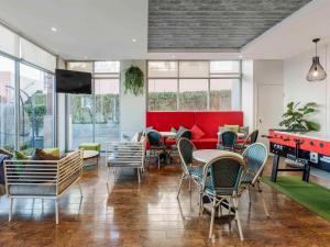 a room with tables and chairs and a red couch at ibis Sydney Darling Harbour in Sydney