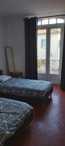 2 Betten in einem Zimmer mit Fenster in der Unterkunft Appartement avec balcon in Malaucène