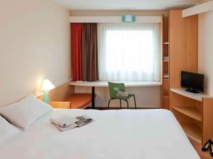 una camera d'albergo con letto bianco e scrivania di ibis Berlin City Potsdamer Platz a Berlino