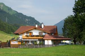 a house in a field next to a mountain at Appartements Schneezauber in Lermoos