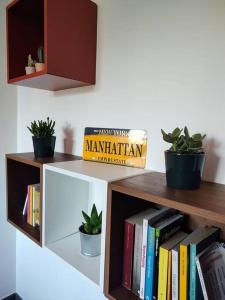 ein Bücherregal mit Büchern und Topfpflanzen darauf in der Unterkunft Bilocale luminoso e accogliente zona Marche in Mailand