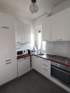 eine Küche mit weißen Schränken und einem Herd mit Backofen in der Unterkunft Bilocale luminoso e accogliente zona Marche in Mailand