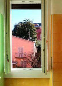ein Fenster mit Blick auf ein rotes Gebäude in der Unterkunft Bilocale luminoso e accogliente zona Marche in Mailand + 35 Fotos