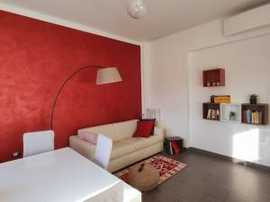 a living room with a couch and a red wall at Bilocale luminoso e accogliente zona Marche in Milan