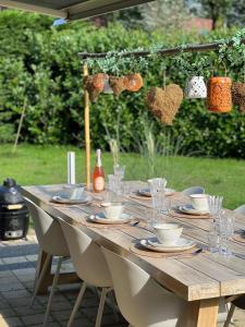een houten tafel met borden en bekers en harten erop bij Villa June Rosy in Wijchen