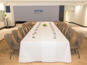 a long table in a room with chairs and a screen at Park Inn by Radisson Bournemouth in Bournemouth