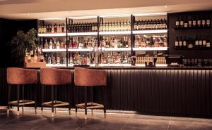 a bar with three chairs and bottles of alcohol at Park Inn by Radisson Bournemouth in Bournemouth