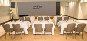 a room with white tables and chairs and a screen at Park Inn by Radisson Bournemouth in Bournemouth