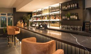 a bar with brown chairs and bottles of alcohol at Park Inn by Radisson Bournemouth in Bournemouth