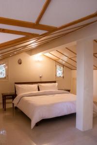 a bedroom with a large white bed with wooden ceilings at BluSalzz Villas - The Pine Tree, Dalhousie - Himachal Pradesh in Dalhousie