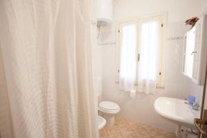 a white bathroom with a toilet and a sink at Appartamenti Villa Anna - Goelba in Capoliveri +17 photos