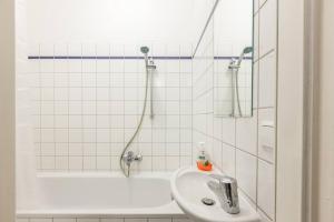 a white bathroom with a sink and a bath tub at Stylish & Tranquil in Berlin