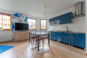 a kitchen with blue cabinets and a table and chairs at Apartament Lazurowy widok - z prywatnym parkingiem - SpaceApart in Karpacz