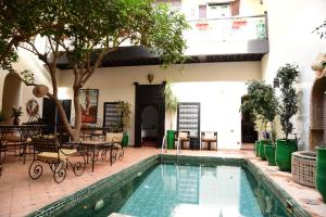 - une piscine avec des tables et des chaises à côté d'un bâtiment dans l'établissement Riad Du Petit Prince, à Marrakech