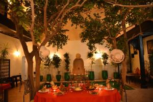 a table with a red table cloth under a tree at Riad Du Petit Prince in Marrakesh