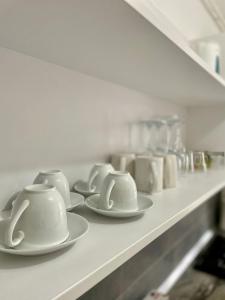 a row of white cups and saucers on a shelf at MontSee Brasov in Braşov