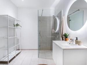 uma casa de banho branca com um lavatório e um chuveiro em Sanders Leaves - Chic Three-Bedroom Apartment In Downtown Copenhagen em Copenhague
