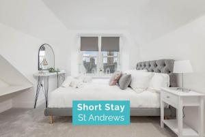 ein Schlafzimmer mit einem weißen Bett mit einem grauen Kopfteil in der Unterkunft Skye Sands - Balgove Penthouse Residence - St Andrews in St Andrews