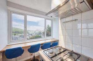 cocina con fogones, sillas azules y ventana en Seaside Retreat sleeping 4 en Ilfracombe