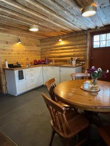 a kitchen with a wooden table and a table and chairs at Salmiņu Pirtsmāja ar relaksējošu baļļu in Pastva Barbern