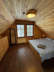 a bedroom with a large bed in a wooden ceiling at Salmiņu Pirtsmāja ar relaksējošu baļļu in Pastva Barbern