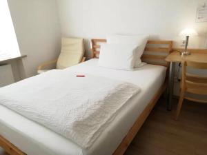 uma cama com lençóis brancos e almofadas num quarto em Hotel Hanseatic-garni em Wuppertal