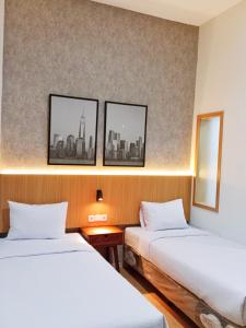 2 camas en una habitación con 3 cuadros en la pared en Hotel Andita Syariah en Surabaya