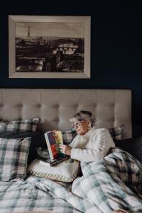 an older woman laying in bed reading a book at Green Gables B&B in Cygnet