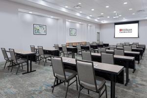 Hilton Garden Inn Charlotte Uptown في تشارلوت: غرفة بها طاولات وكراسي وجدار أبيض