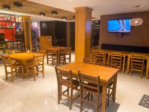 a restaurant with wooden tables and chairs and a tv at Los Lagos Resort Hotel in Capiatá