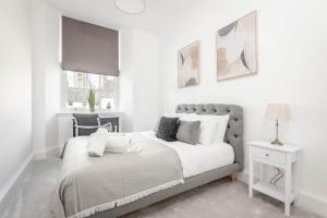 a white bedroom with a bed and a chair at Skye Sands - The Eden Residence in St. Andrews